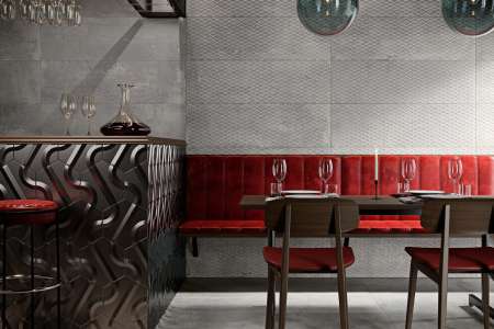Interiér restaurace s šedými obklady a dlažbou ze série Aparici Metallic.